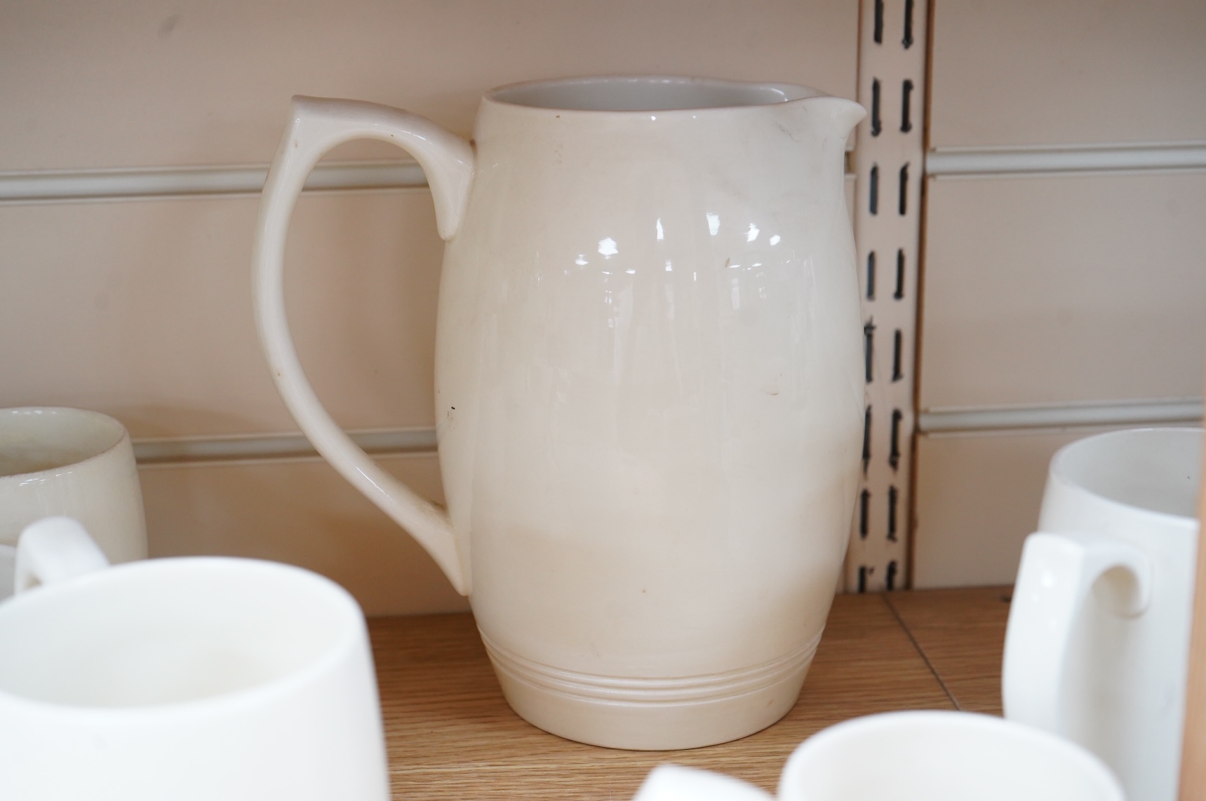 Keith Murray for Wedgwood, a cream lemonade jug, five small mugs, two large three faceted, largest 21cm high (12)
